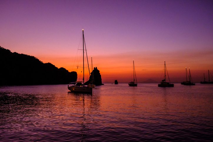Sunset in the bay of the Aeolian Lipari Island Vulcano with sailing boats against the horizon