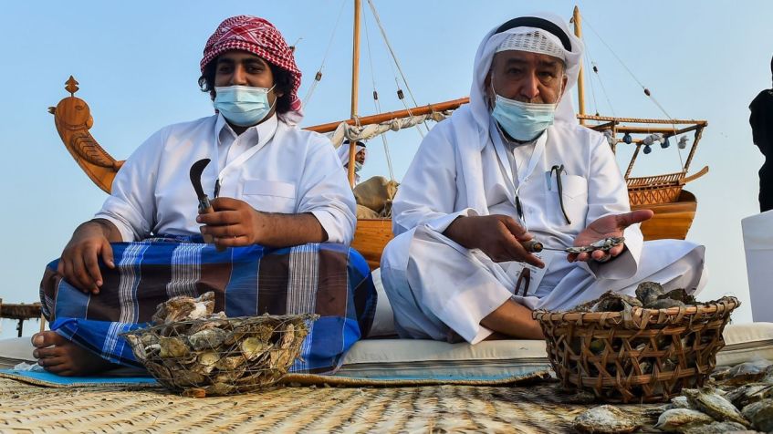 Homens do Catar abrem ostras e extraem pérolas durante o Katara Traditional Dhow Festival / Getty Images
