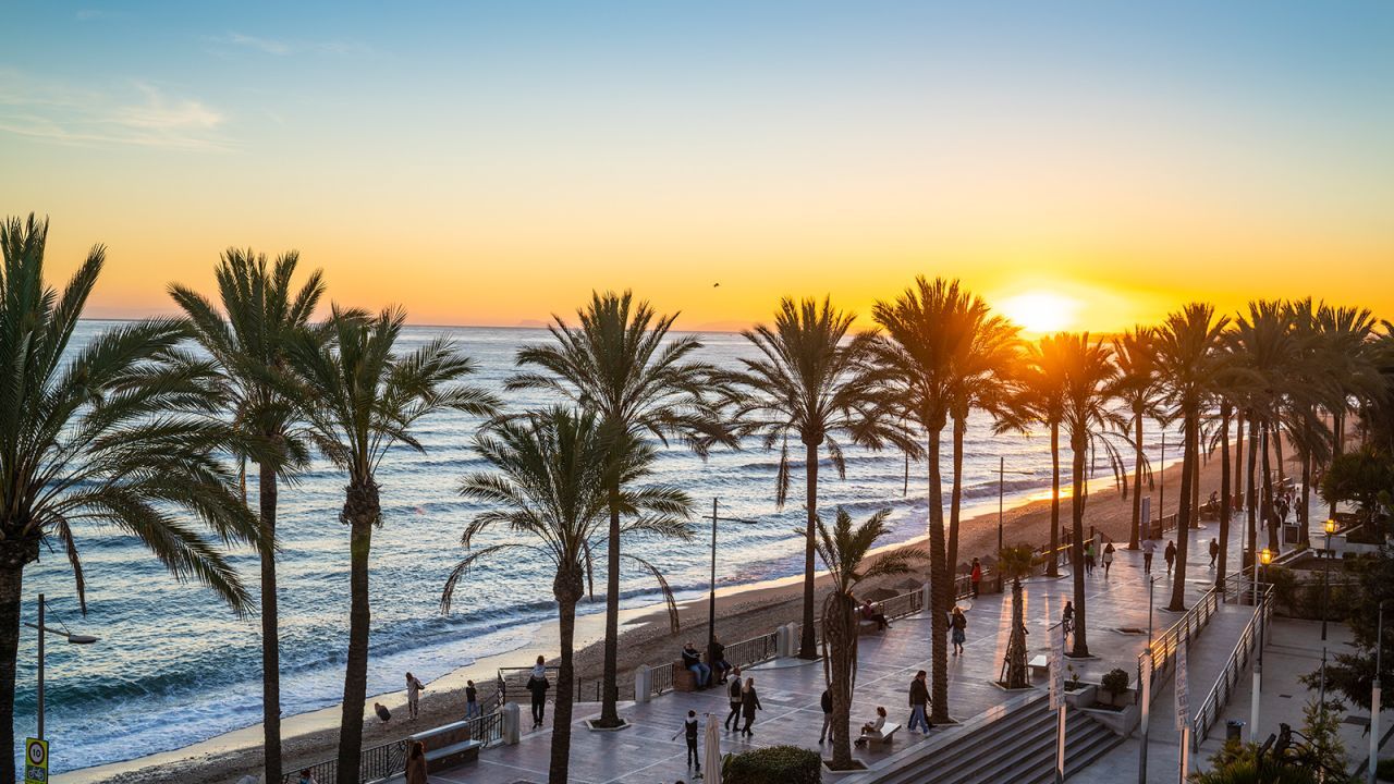 As pessoas passeiam ao pôr do sol ao longo da Playa de la Fontanilla em Marbella / Mediterranean/iStock Unreleased/Getty Images