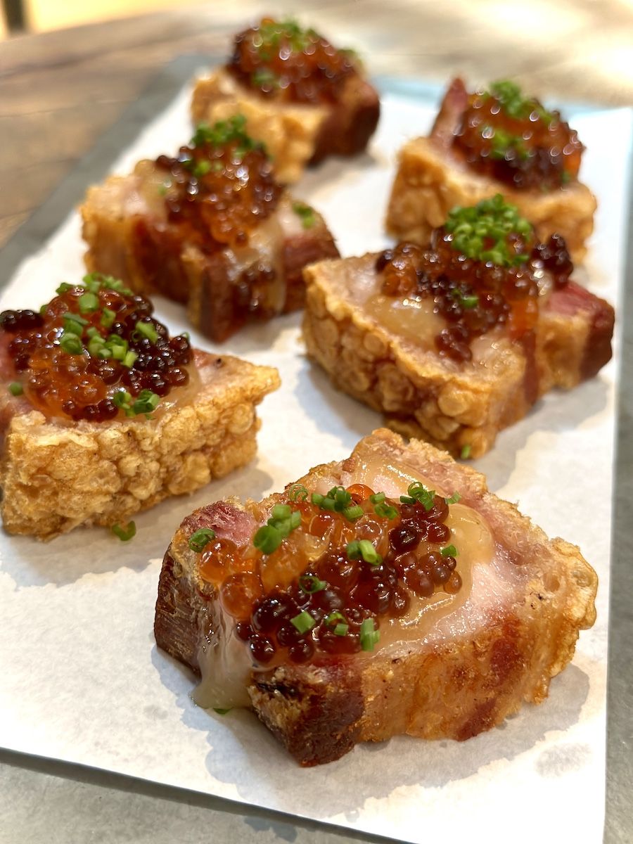 Barriga de porco defumada e servida com picles de cebola roxa, chutney de cupuaçu com pimenta Baniwa e ovas de salmão / Tina Bini