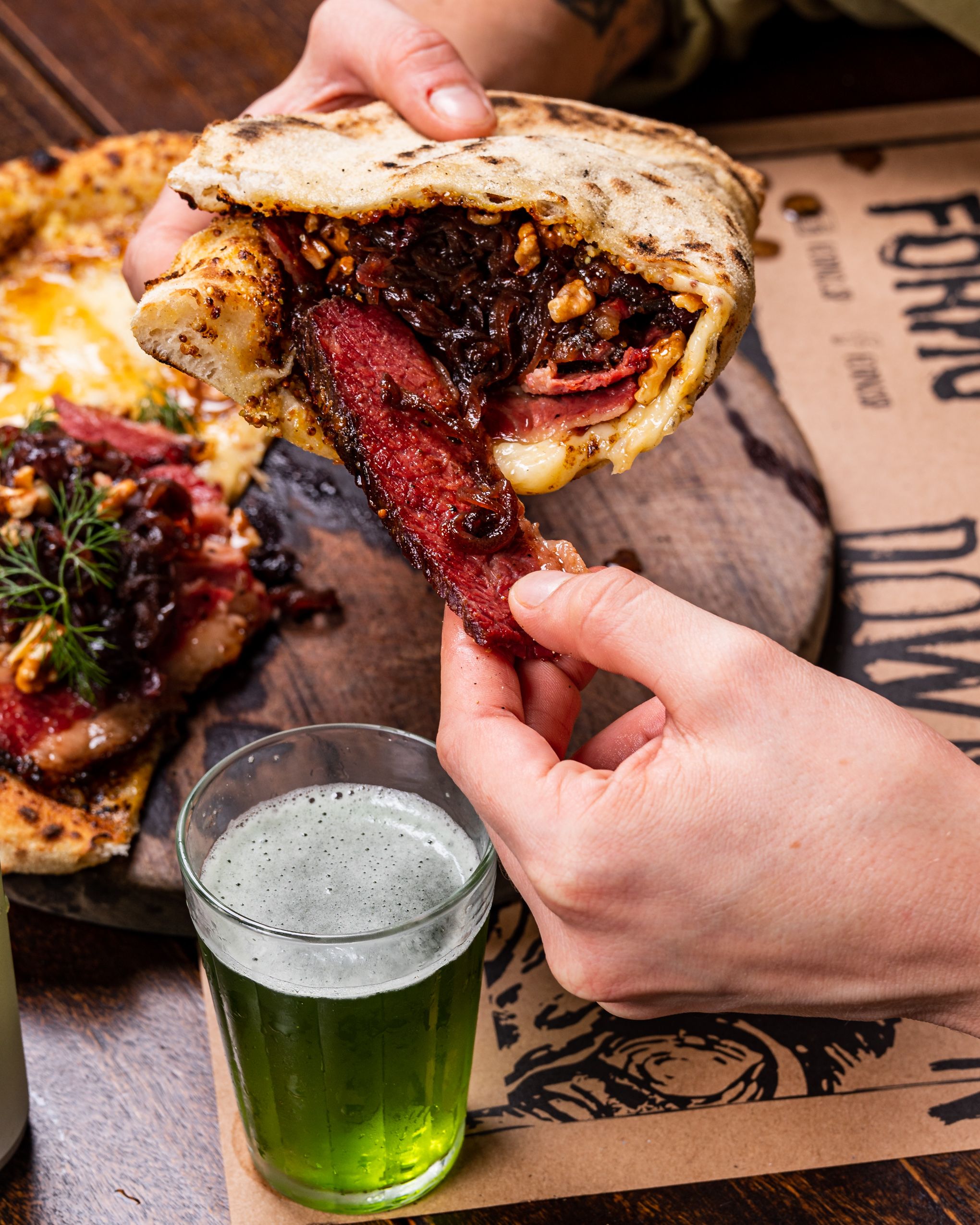 Origami, pizza feita com mostarda anciene na base, mozzarella, parmesão, pastrami, cebola roxa caramelizada, nozes, passas, dill e mel picante para comer dobrado como se fosse um sanduíche / Matheus Vassato