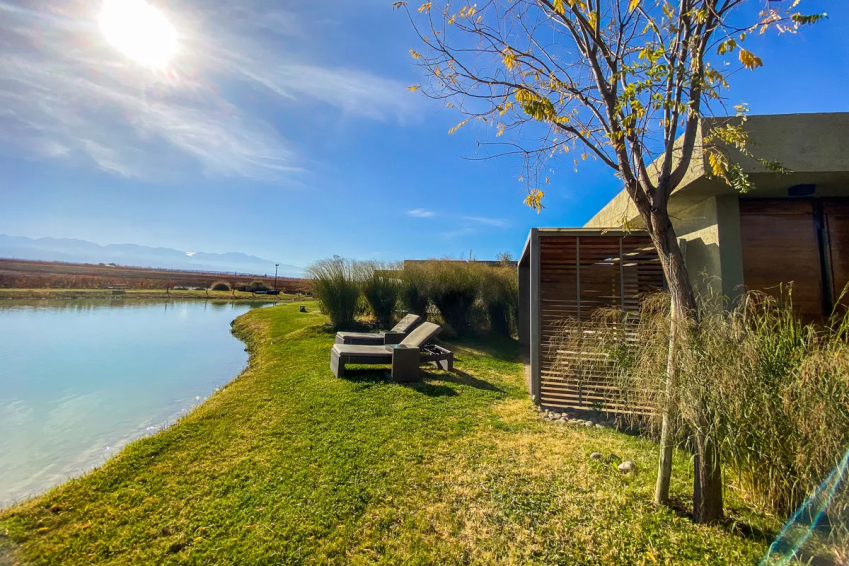 Uma das acomodações da Casa Petrini com espreguiçadeiras à beira do lago / Reprodução/Site