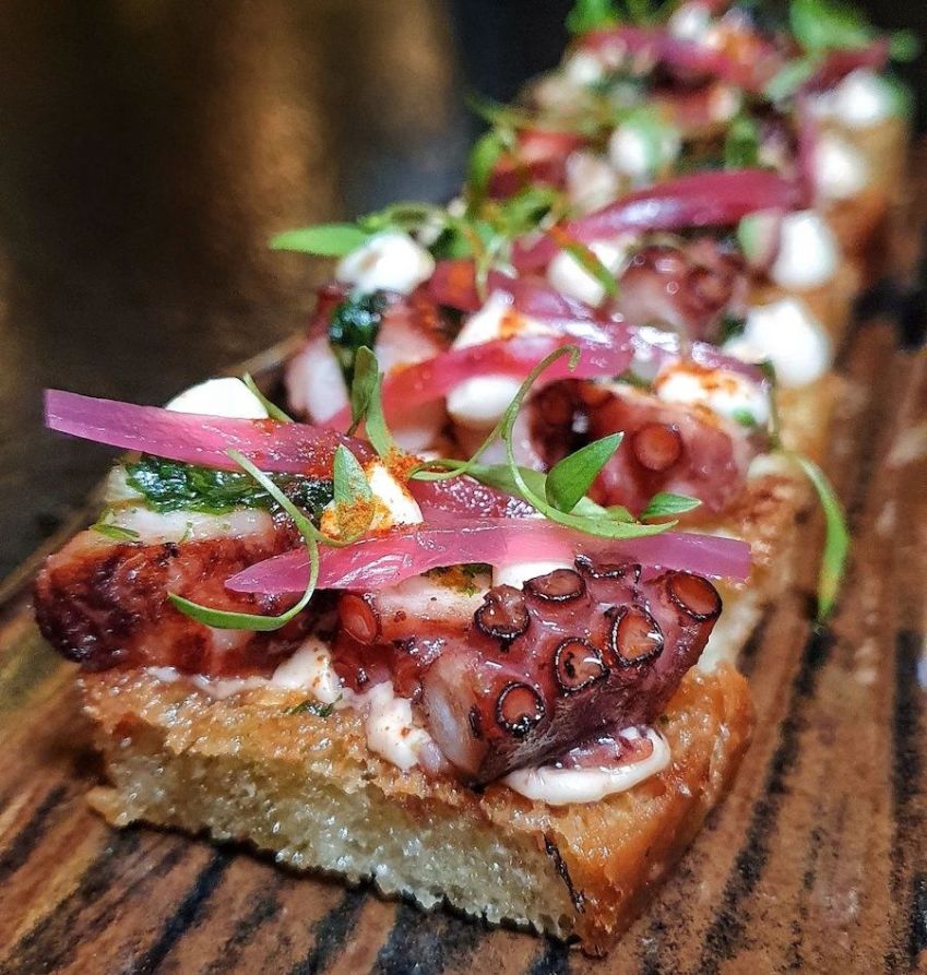 Polvo com salsa verde, aioli picante e picles de cebola roxa na focaccia feita na casa / Caroline Grimm