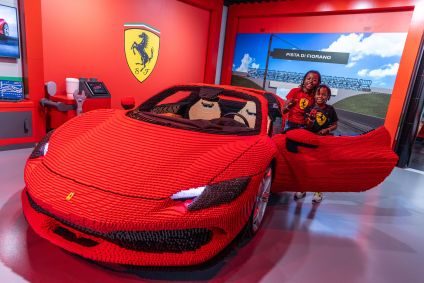 Crianças posam com o único modelo de uma Ferrari 296 GTS feita inteiramente de LEGO
