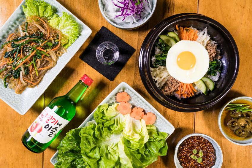 Mesa com delícias asiáticas e uma garrafa de Soju, destilado coreano / Pexels