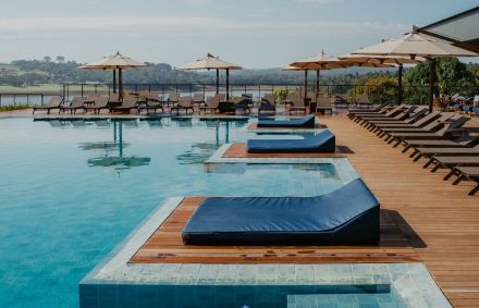 Área da piscina com móveis e guarda-sóis do resort Clara Ibiúna