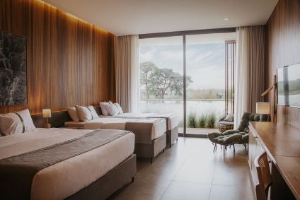 Camas de casal e móveis com vista para o lago de um dos apartamentos do Santa Clara Eco Resort