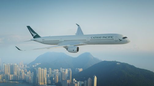 Avião da Cathay Pacific sobrevoando cidade