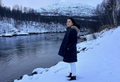 Daniela Filomeno de frente para rio e paisagens com gelo na Lapônia Norueguesa