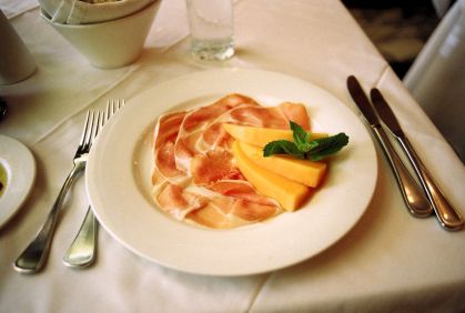 Prosciutto di San Daniele em um prato junto de pedaços de melão