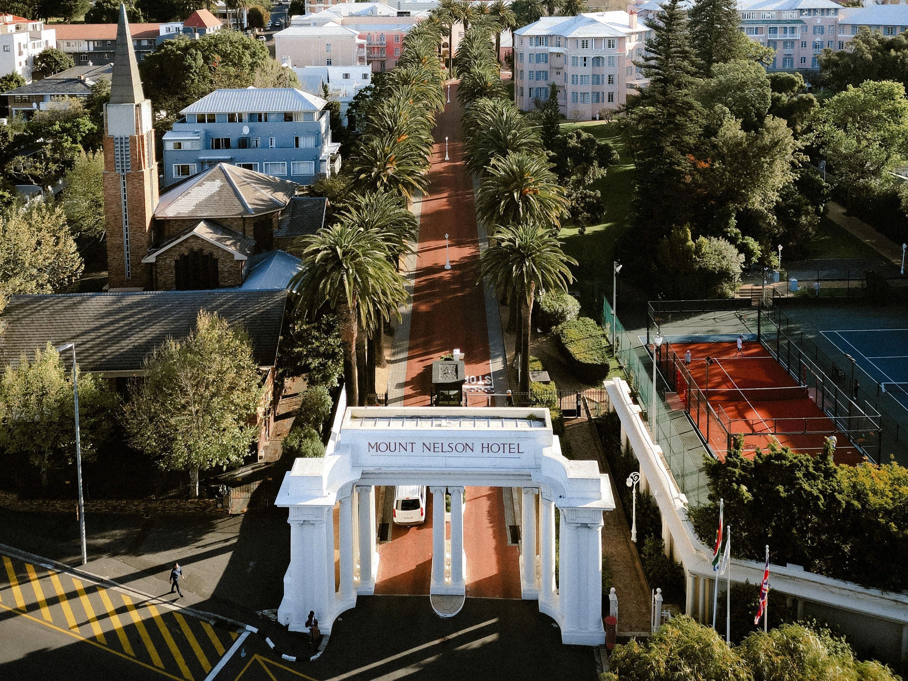 Entrada do hotel Belmond Mount Nelson, com colunas de pedras e palmeiras • Divulgação/Belmond