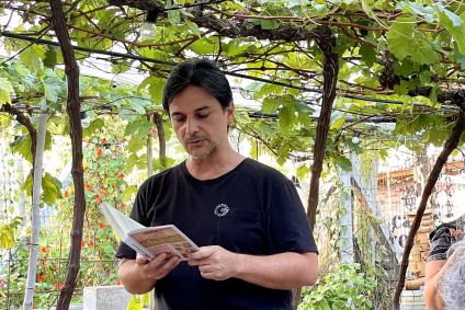 Alessander Guerra, o Cuecas na Cozinha, lê livro embaixo de um parreiral