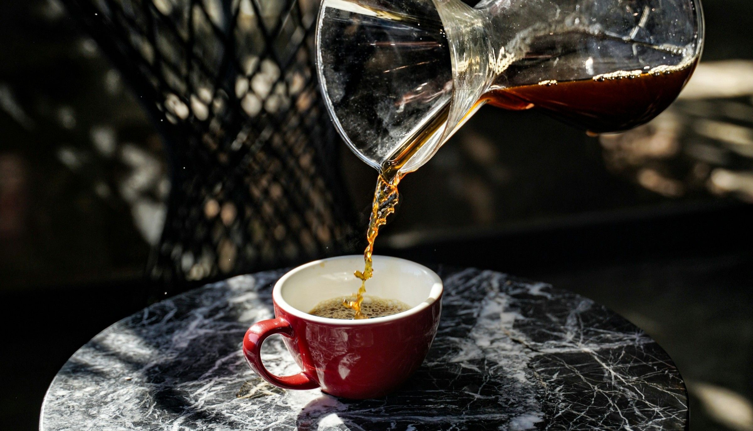 Café sendo despejado em xícara em uma cafeteria