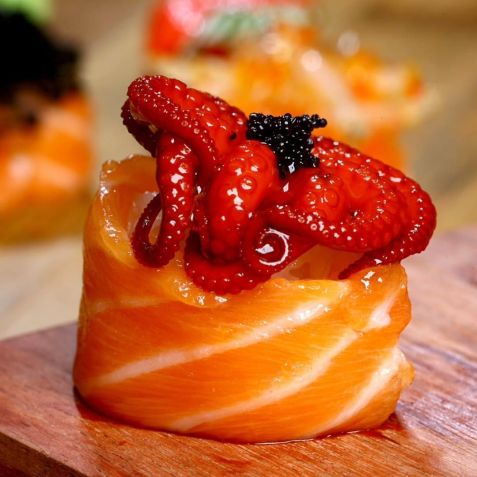 Mini polvo japonês marinado em molho tradicional, sobre arroz de sushi envolto em lâmina de salmão • Instagram/Haru Ichiban