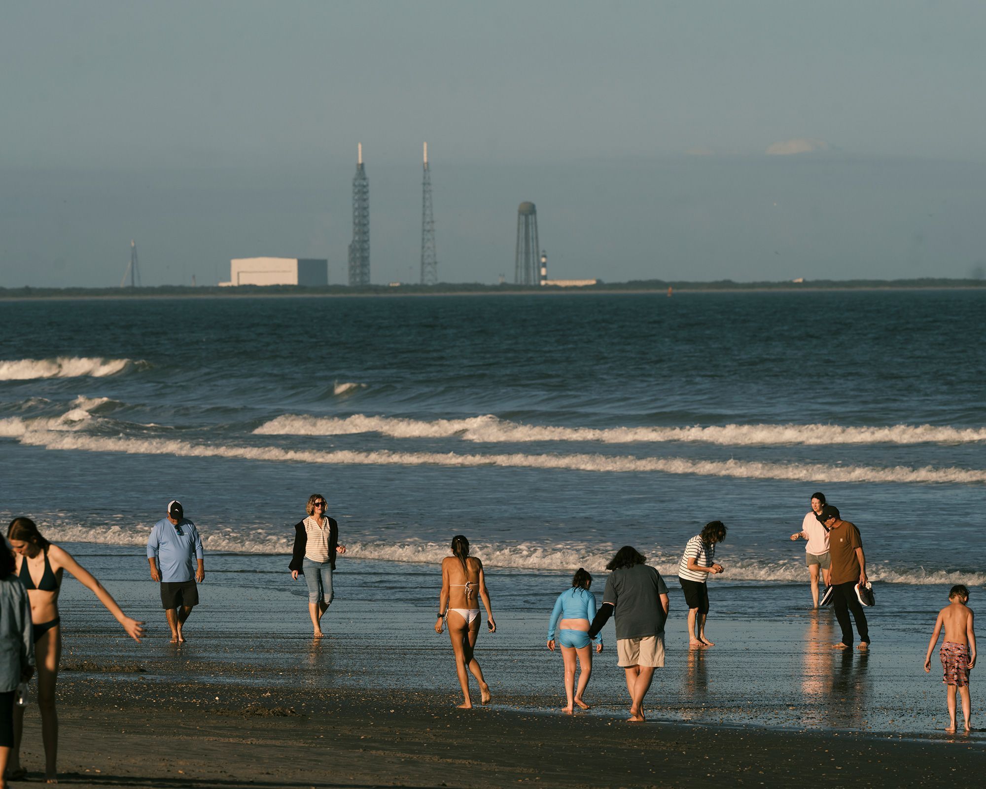 Em janeiro, banhistas aproveitam a areia e as ondas de Cocoa Beach enquanto plataformas de lançamento de foguetes se erguem nas proximidades • Zack Wittman for CNN via CNN Newsource