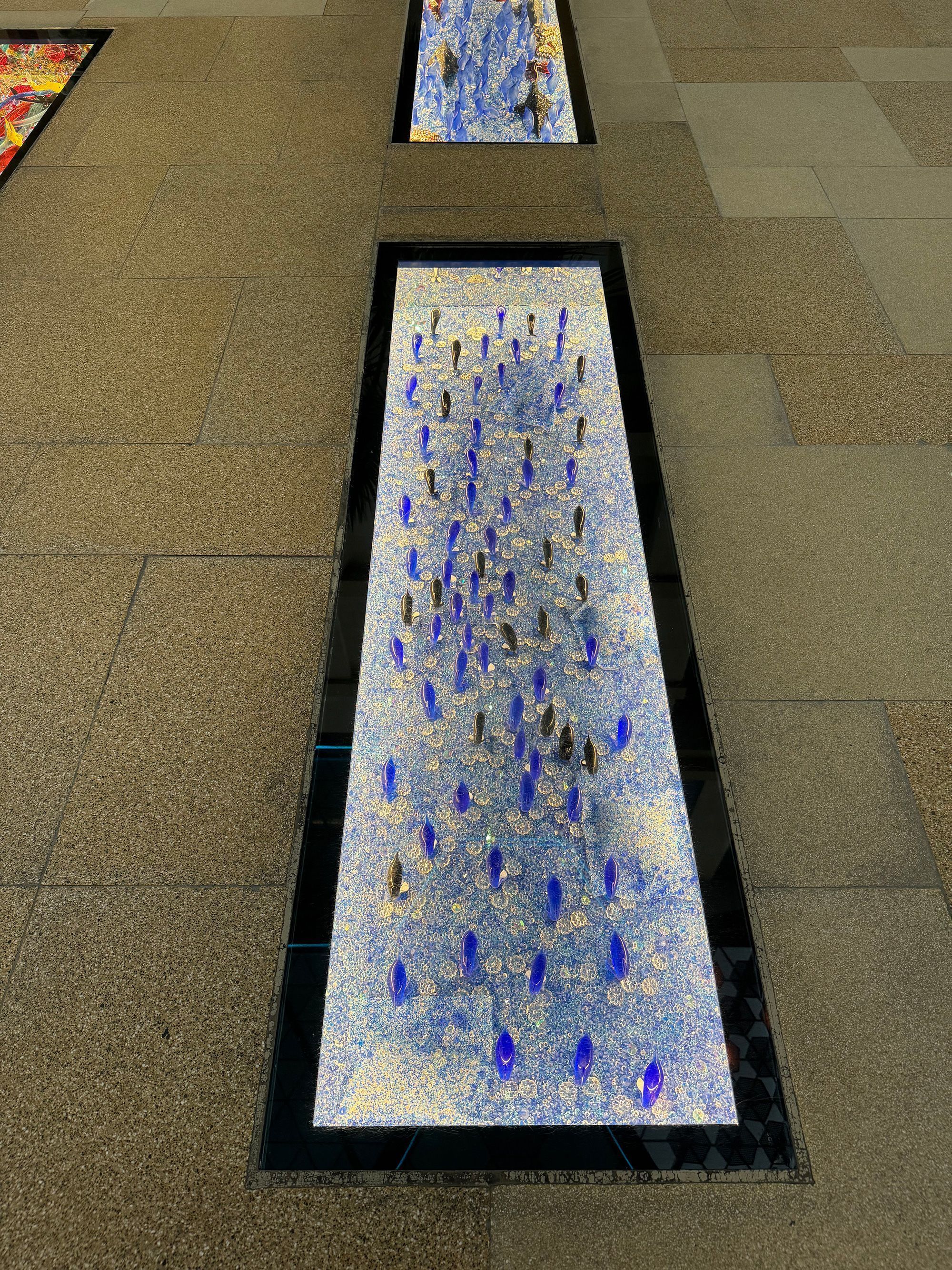 Painéis de cristal no piso da passarela exibem obras de arte e peças culturais • Ulrike Lemmin-Woolfrey via CNN Newsource