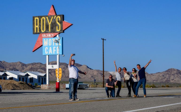 Turistas franceses tiram uma selfie em grupo em frente à placa do Roy's Motel & Cafe em 24 de maio de 2024, em Amboy, Califórnia • Gina Ferazzi/Los Angeles Times/Getty Images via CNN Newsource