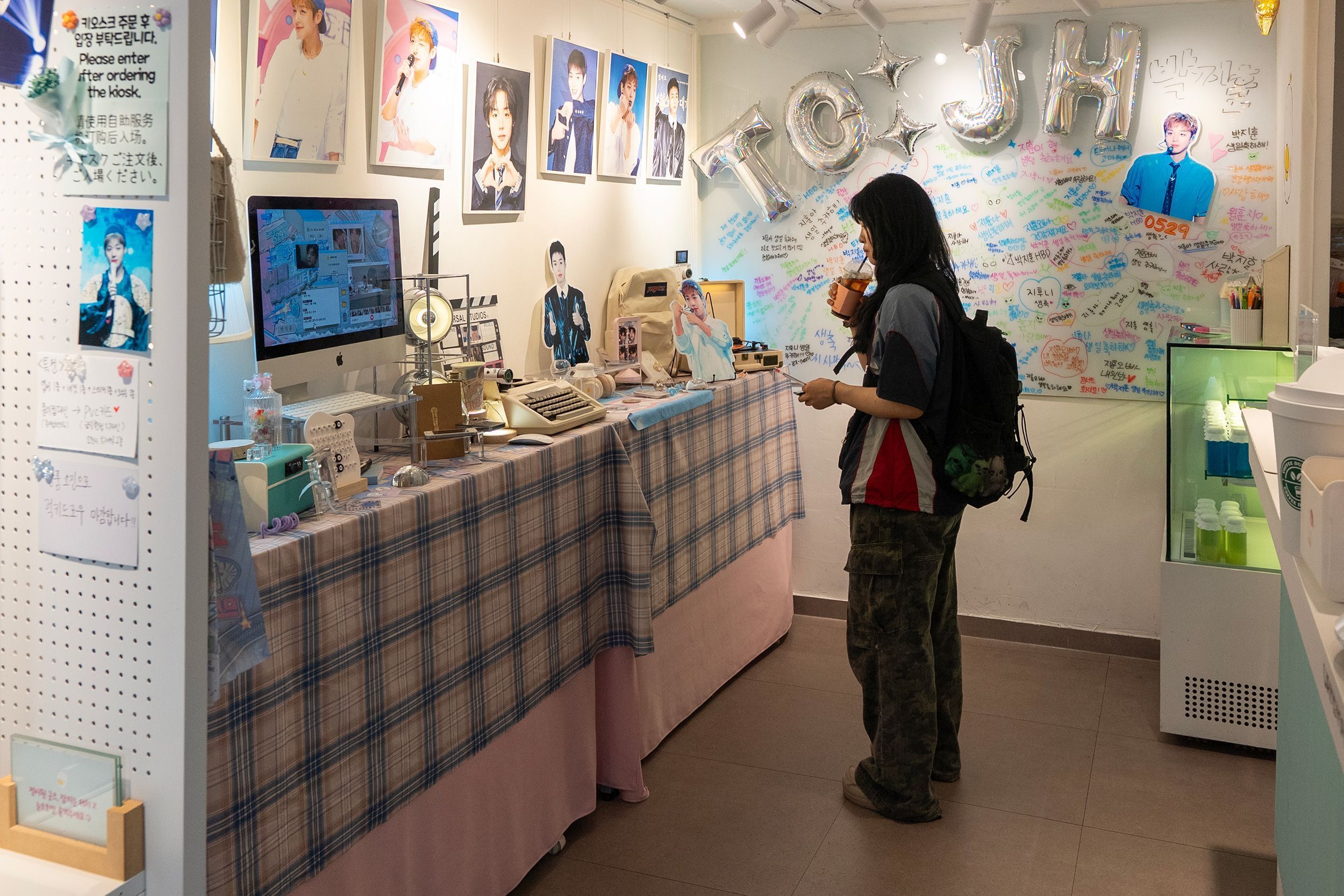 Uma fã observa uma vitrine com produtos e fotos dentro do café de aniversário de Park Ji-hoon • Charlie Miller/CNN via CNN Newsource