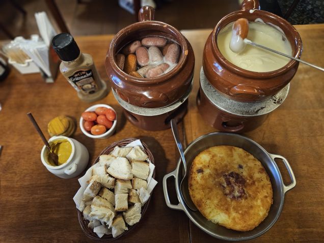 O fondue de queijo chega acompanhado de minisalsichas, pão italiano, tomate-cereja e mostarda. Ainda é possível acrescentar batata rösti • Divulgação