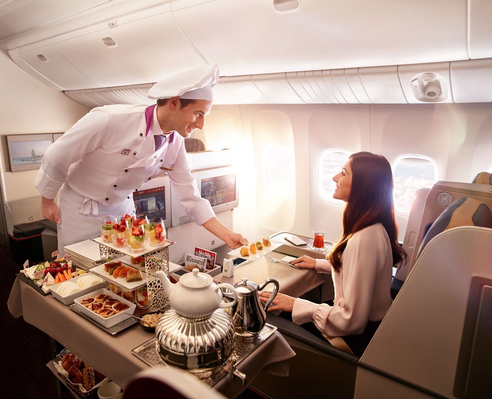 Chef a bordo servindo os passageiros da classe executiva da Turkish Airlines diretamente de um carrinho repleto de opções • Divulgação