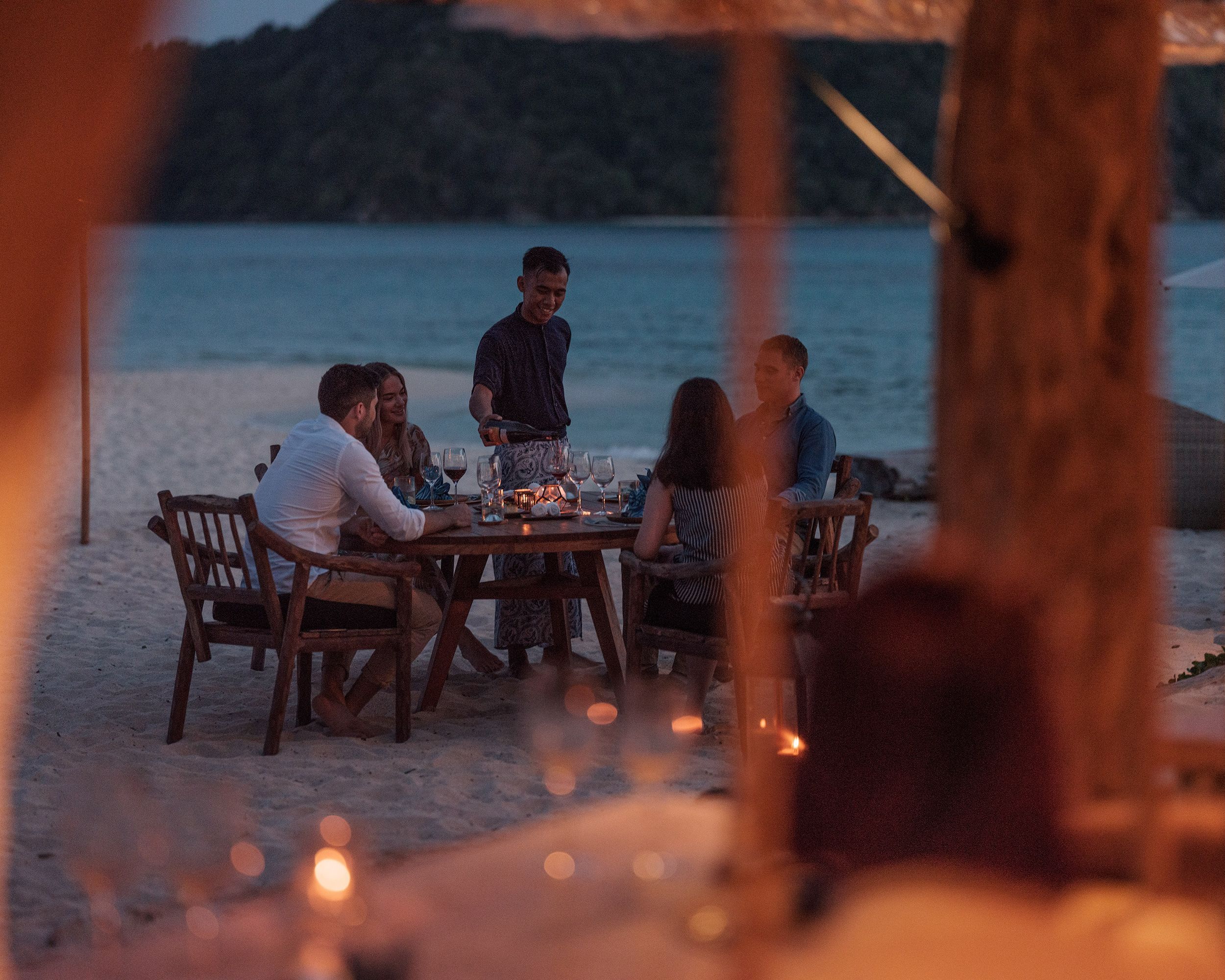 Um garçom serve vinho no The Boathouse, um dos dois restaurantes da ilha • Cortesia Bawah Reserve via CNN Newsource