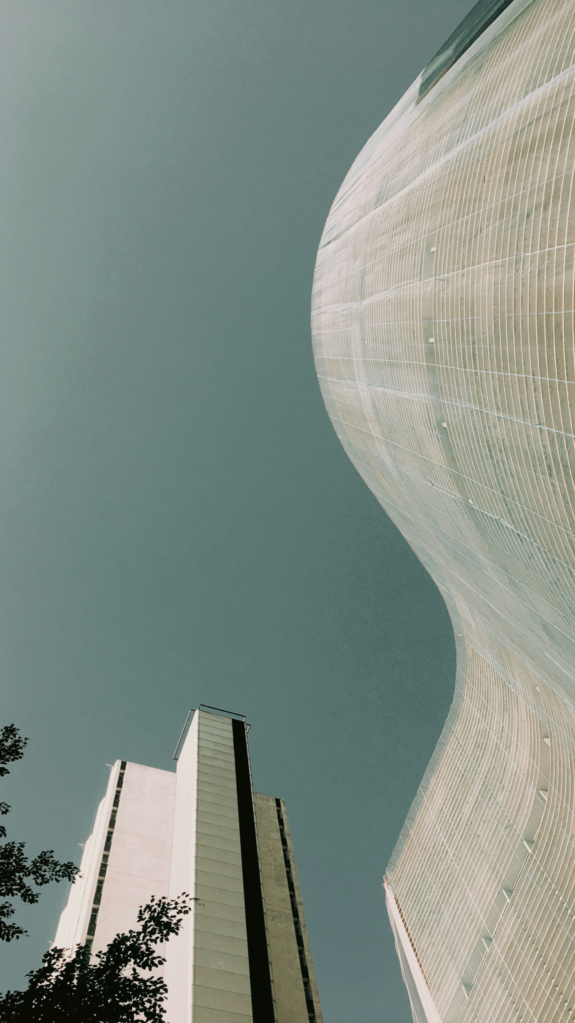 Edifício Copan, um dos maiores símbolos da arquitetura de São Paulo, visto de baixo, com destaque para suas curvas e fachada característica • Foto de Caio Arbulu na Unsplash