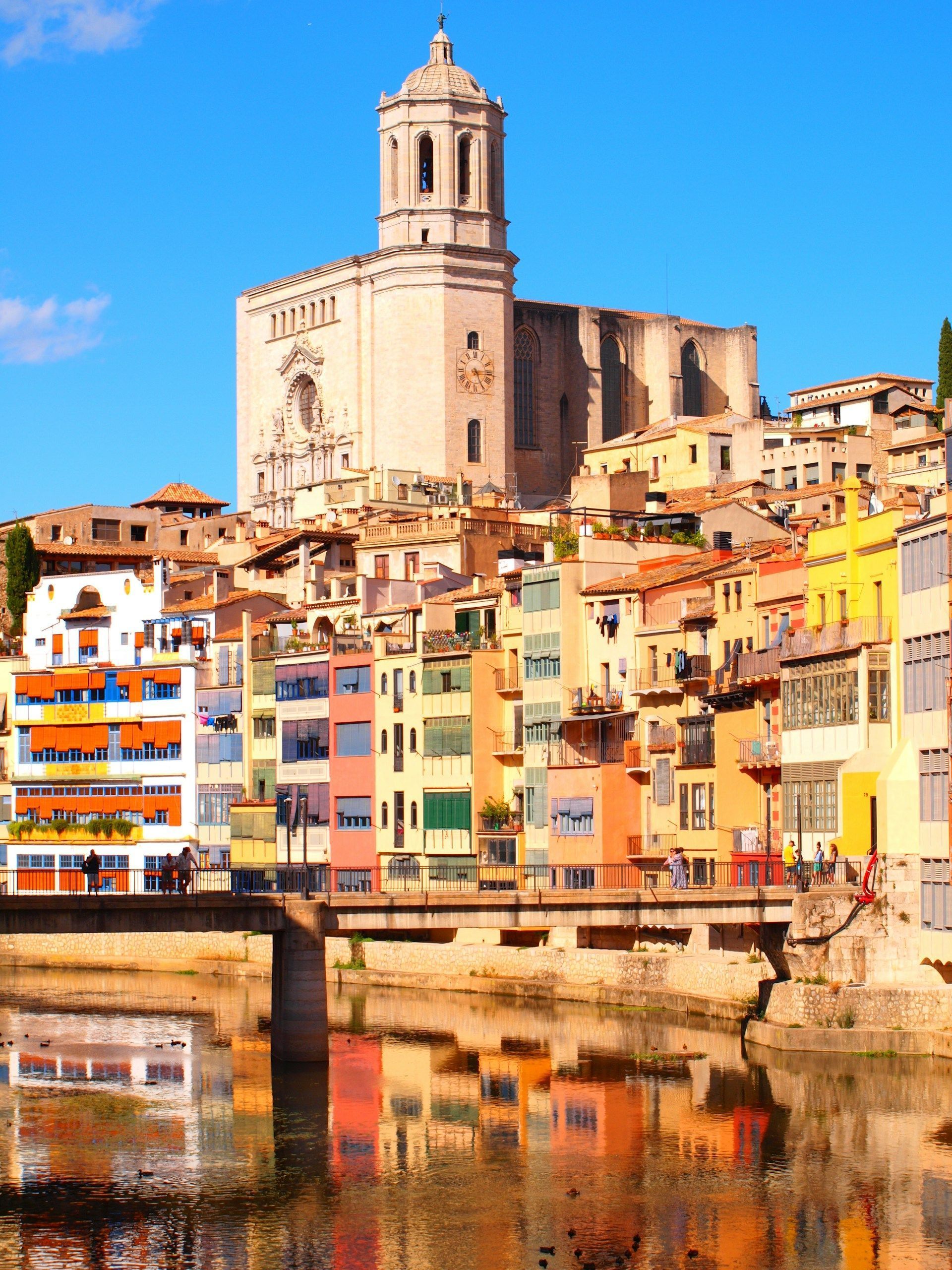 Catedral, no ponto mais alto da cidade, e as fachadas coloridas de Girona, formam cartão-postal junto do rio Onyar • Foto de Miko Rohat na Unsplash